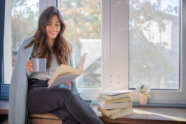 istock Happy woman reading book at home 1440614462
