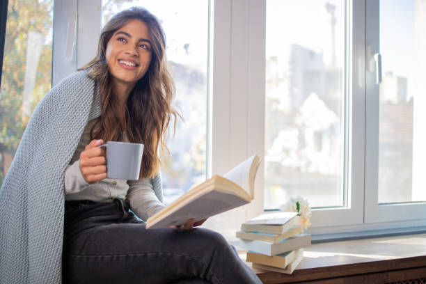 istock Happy woman reading book at home 1440614495