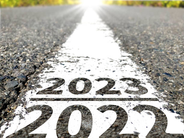 Proceed from 2022 to 2023. On the white line of the road, 2022 and 2023. There is a bright light in the distance. new years day photos stock pictures, royalty-free photos & images