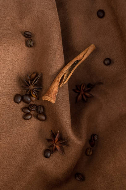 An elegant composition of spices - with anise, cinnamon on a suede brown background with beads and pearls