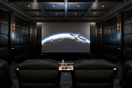 The interior of the private movie theater of a luxury mansion with leather recliners, built-in ceiling speakers and large projection screen.\n(World map texture courtesy of NASA: https://visibleearth.nasa.gov/view.php?id=55167)