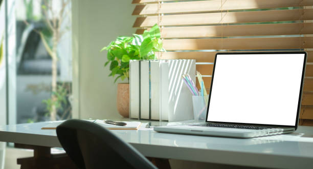 istock Computer laptop with empty screen, books, coffee cup and houseplant on white table. 1440628880