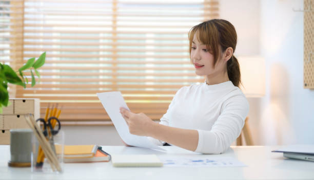 istock Focused young businesswoman checking financial reports while working at modern home office. 1440630629