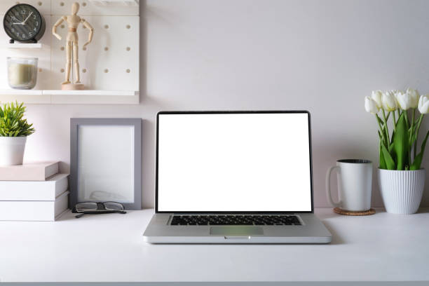 istock Front view laptop, alarm clock, books and potted plant on white office desk. Creative workplace. 1440632671