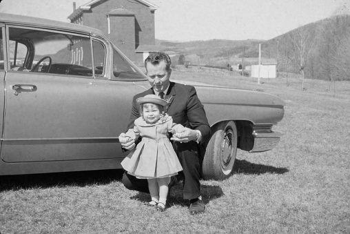 A father and one year old daughter posing in from of a car on Easter Sunday 1962.