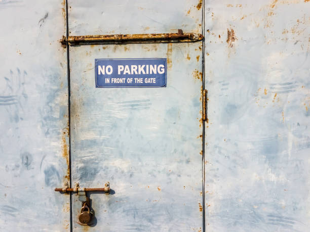 a no parking sign outside a rusty locked metal door - sign rusty industry no parking sign imagens e fotografias de stock