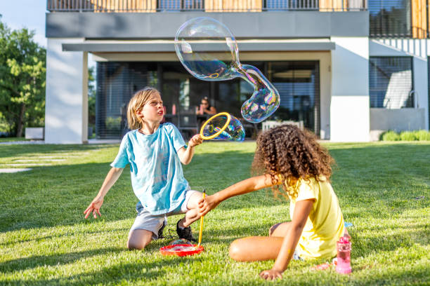 istock Multiracial kids blowing big soap bubbles in backyard 1440641130