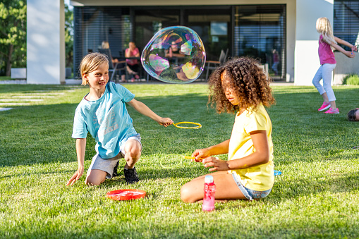 Little pretty girls having fun outdoor. Two cute girls are running on green grass with air balloons. Best friends