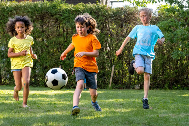 istock Active children running, playing football outdoors, kicking ball 1440641274