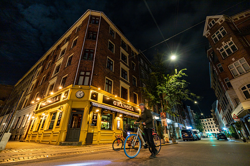 Copenhagen, Denmark Oct 13, 2022 A man stands with a bike near a landmark restaurant called Granola on Vaernedamsvej in Vesterbro at night.