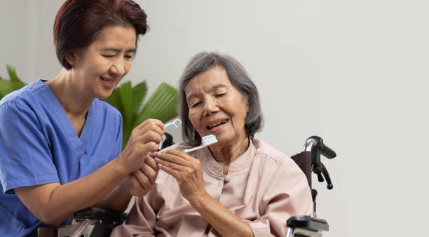 Caregiver take care asian elderly woman while brush teeth. stock photo