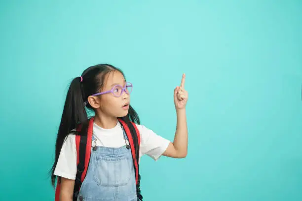 Photo of Close-up kid schoolgirl Pointing Fingers At Copy Space.