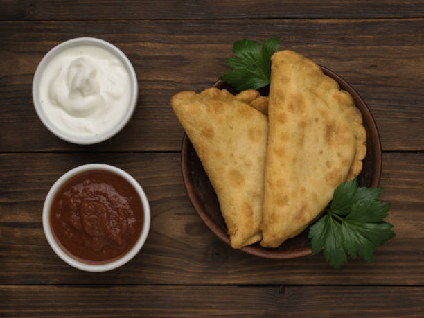 istock Bowls with red and white sauce and fried pasties on a wooden table. 1440647209