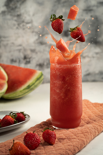 Flavor explosion. Splashing strawberry and watermelon smoothie. Drops and fruit flying.