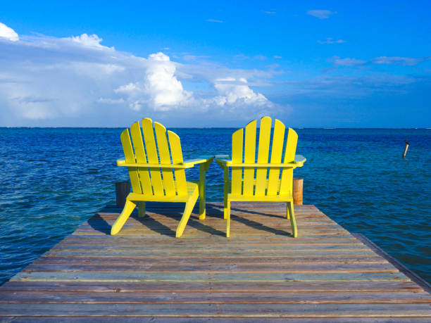 istock Two empty chairs on a dock looking out toward tropical water paradise 1440650729