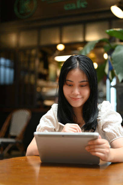 istock Asian woman using her digital tablet while relaxing in the beautiful coffee shop on her weekend. 1440655924