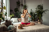 Young sporty woman practicing yoga at home,sitting in Lotus position,namaste hands.Relaxation and meditation.Wellness,wellbeing,mental health concept