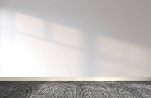 istock Front view of empty room with white wall, baseboard and black carpet floor in sunlight from window 1440660711