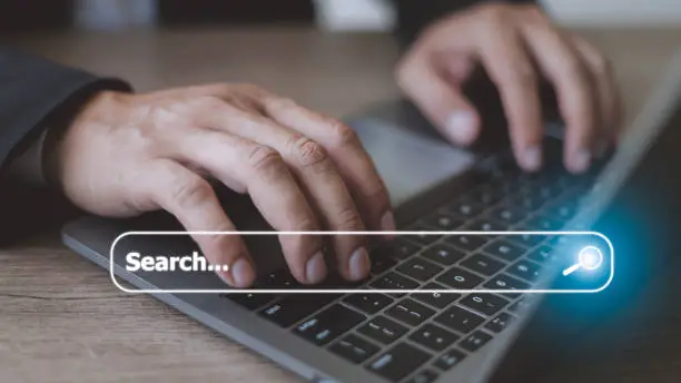 Photo of People hand using laptop or computor searching for information in internet online society web with search box icon and copyspace.