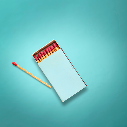 Overhead shot of opend old blue matchbox with match stick on light blue background.