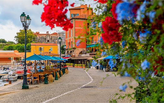 Seaside promenade with flowers and traditional houses along Mediterranean Sea in Villefranche sur Mer Old Town on the French Riviera, South of France