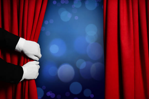 istock Man opening red front curtains against blurred lights. Bokeh effect 1440679838