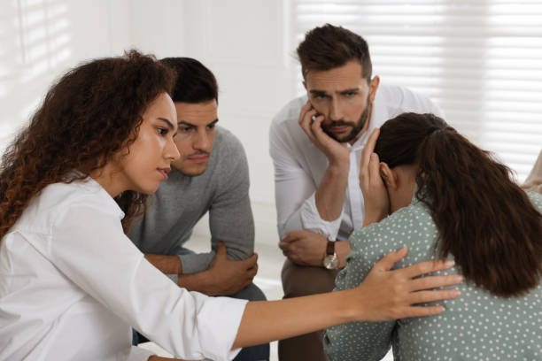 Psychotherapist working with patient at group session indoors