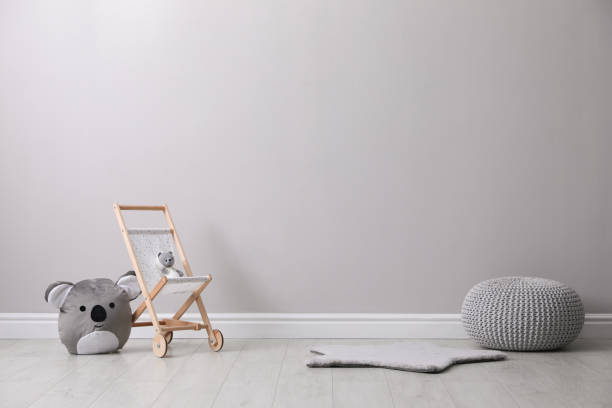 istock Toy stroller with bear and pouf near grey wall in child room. Interior design 1440680016