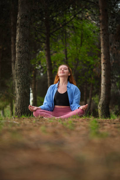 istock Redhead young woman meditating in a forest. 1440680426
