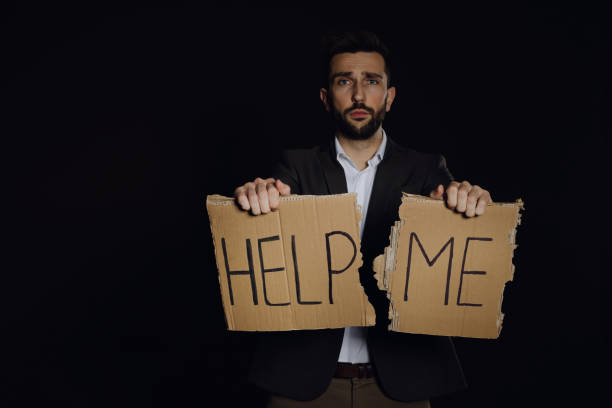 istock Unhappy man with HELP ME sign on dark background 1440681139