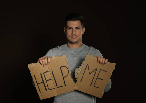 istock Unhappy man with HELP ME sign on dark background 1440681618
