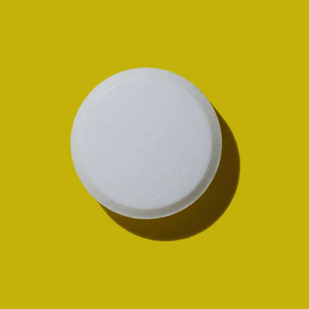 istock Single white pill on a colored yellow background. Hard light, shadow. Top view, copy space 1440681841