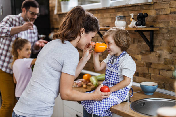 istock Playful mother and son having fun with vegetables in the kitchen. 1440683047
