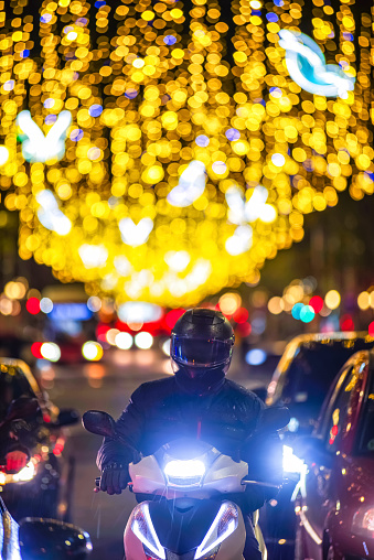 Motorbike and cars at rush hour with traffic at night  with Christmas lights on Passeig de Gracia, Barcelona, new year decoration in the city.