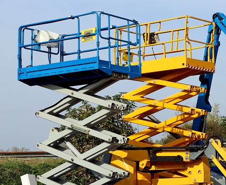 Two scissor elevators, a type of  aerial working platforms. Sky on background.