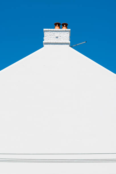 Close-up on a side wall of a building with chimney and deep blue sky beyond.