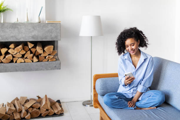 Young Black woman relaxing at home using mobile stock photo