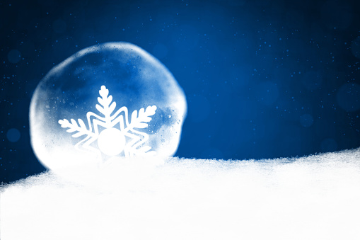 Horizontal illustration of a white snowflake shape in fading color packed in a bubble over smoke or snow. Apt for Xmas, Christmas, New Year Day vacations themed wallpapers, greeting cards, posters and backdrops and gift wrapping paper sheets.