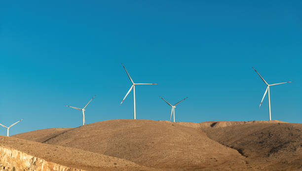 istock Multiple wind turbines standing on a hill at sunrise and generating electricity 1440697486