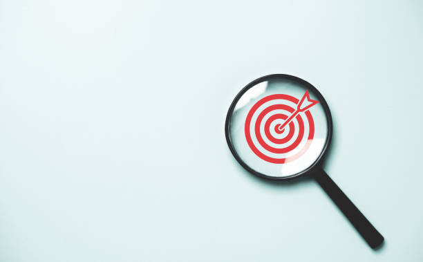 Red dartboard inside of black magnifier glass on blue background for setup objective target and business goal concept. Red dartboard inside of black magnifier glass on blue background for setup objective target and business goal concept. return on investment photos stock pictures, royalty-free photos & images