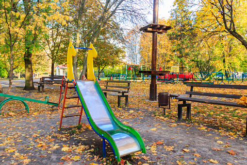 Colorful playground equipment for children in public park at autumn