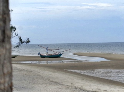 Khao Takiab Beach in Hua Hin with a small fishing boat grounded due to low water