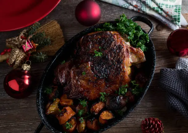 Delicious homemade christmas meat dish with roast turkey shank, vegetables and sauce. Served ready toeat on rustic and wooden table background from above with decoration and ornaments.