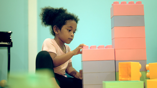 A little girl plays with blocks in the playroom.