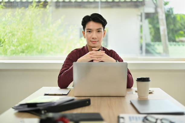 istock Successful young businessman sitting front of laptop computer and looking confidently to camera. 1440700690