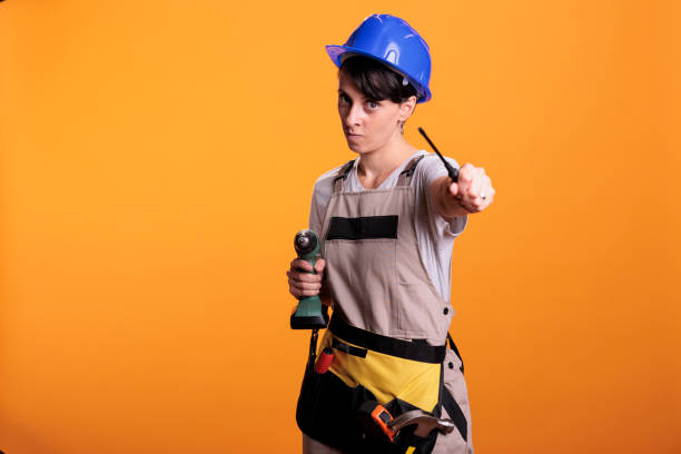 istock Focused female contractor holding drilling gun and screwdriver 1440701311
