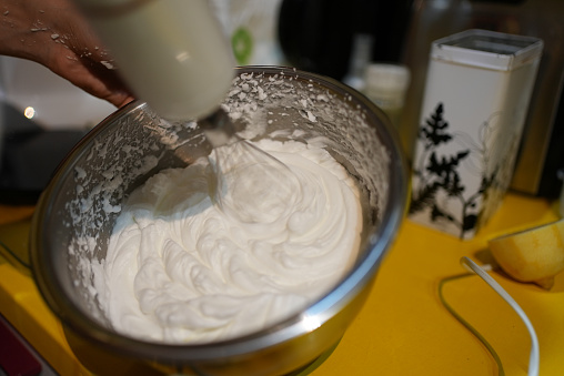 Side angle of hand mixer stirring up a white cream