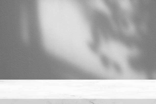 istock Marble Table with Leaves Shadow on Stucco Wall Texture Background, Suitable for Product Presentation Backdrop, Display, and Mock up. 1440703329