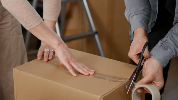 istock Couple using adhesive tape to pack things in cardboard boxes 1440703867