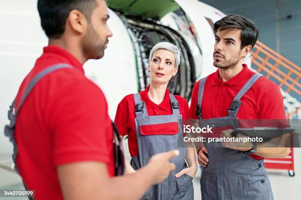 Airplane Mechanics Discussing Planned Aircraft Maintenance In A Hangar Stock Photo - Download Image Now
